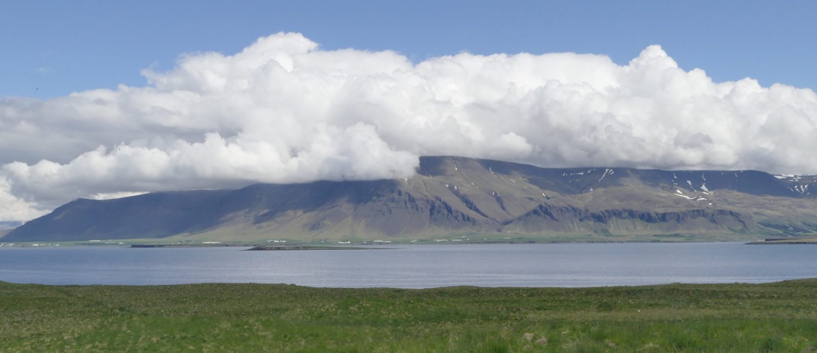 The view from Viðey north over the bay to the Esja mountain ridge, with a big white cloud low over it.